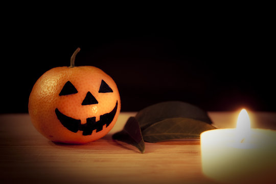 Tangerine - Halloween pumpkin with candle and leaves on a dark background. Still life picture taken in studio.