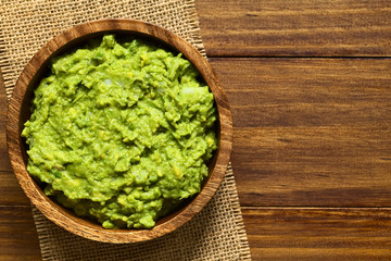 Avocado dip or guacamole in wooden bowl, photographed overhead with natural light (Selective Focus, Focus on the avocado dip) © Ildi