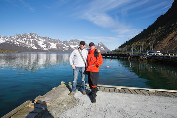Two men standing on the pier. Behind the mountains.