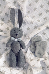 gray toy rabbit lies next to a gray socks