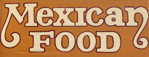 MEXICAN FOOD sign on brown wall.
