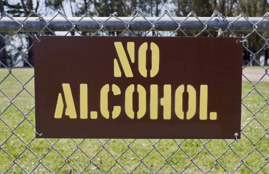 NO ALCOHOL sign attached to public park fence.