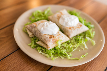 Fototapeta na wymiar Chimichangas on salad with cream on top.