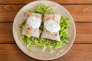 Chimichangas on salad with cream on top.