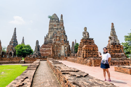 Tourist teenage girl show hand inviting to visit Wat Chaiwatthanaram is buddhist ancient temple, famous and major tourist attraction religion, Phra Nakhon Si Ayutthaya Historical Park, Thailand