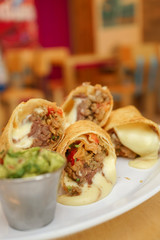 Flour tortilla burrito with beef, avocado and melted cheese, typical Mexican dish.