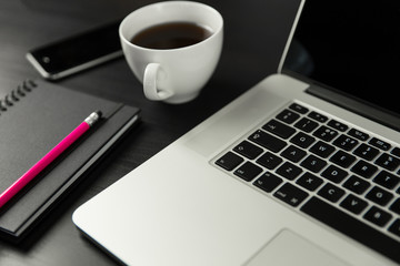 Laptop, coffee cup, mobile phone on black designer desk