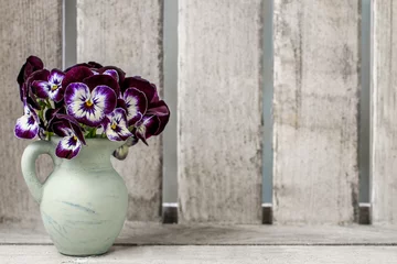 Poster Bouquet of pansy flower in ceramic vase. Wooden background © agneskantaruk