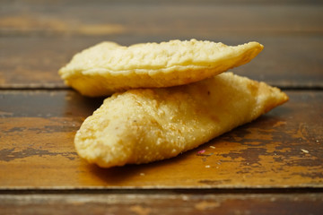 Argentinian empanadas stuffed with melted cheese on an old wooden table.