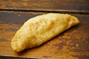 Argentinian empanadas stuffed with melted cheese on an old wooden table.