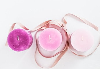 Three pink ombre scented candles with ribbon on white. Woman decorating ideas. Beauty blogger flat lay concept. Copyspace