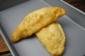 Argentinian empanadas stuffed with melted cheese on an old wooden table.