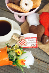 Heart shaped cookies and chocolate candies (big and small as couple), cup of coffee, bouquet of flowers decoration. sunny morning. Romantic breakfast or Valentine's Day Breakfast. Toned image 