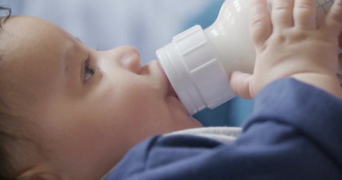 Baby Bottle Feeding Profile Slow Motion. a slow motion close up of a 3 month old baby feeding from a bottle on a profile side angle
