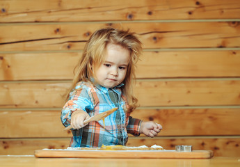 cute child cooking with dough, flour holds wood shovel