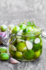 Pickled  Brussels sprouts with garlic in glass jar on wooden tab