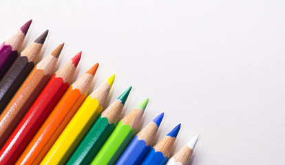 Colored pencils laying next to eachother in color order on a white background