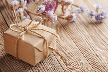 Gift box in kraft paper with bow on wooden background
