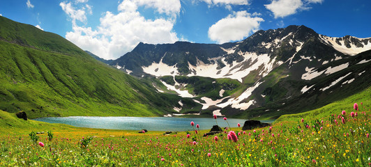 Mountain Lake in the Caucasus summer. Blue sky with white clouds.