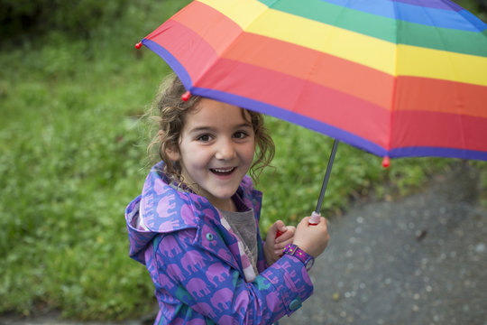 Girl holding rainbow umbrella and smiling