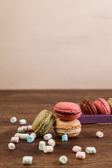 Macaroon cakes with colorful fluffy marshmallows. Almond sweet cookies. Wooden rustic board.