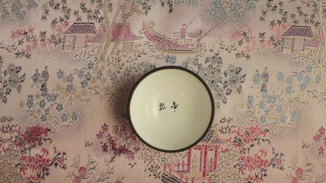 Pour tea from teapot into a chinese cup overhead shot