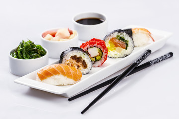 various kinds of sushi on a white plate, chopsticks, wasabi, pic