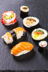 Set of various kinds of sushi on a black stone