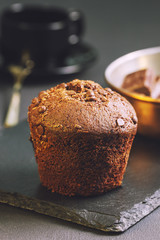 Chocolate muffin and a cup of coffee on a dark table