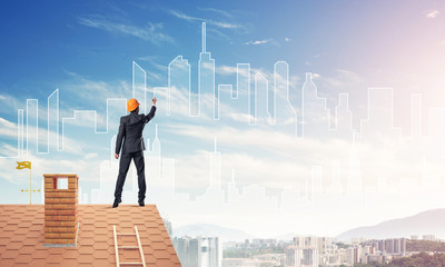 Man architect draw silhouette of modern city on blue sky. Mixed 
