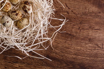 Quail eggs in straw nest. Natural organic eco food. Wooden rustic background.