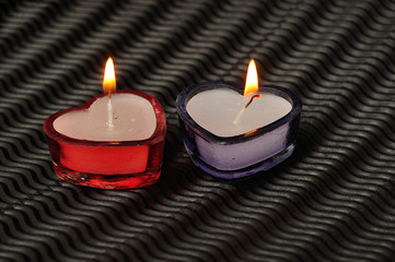 Two heart shape candles displayed on a black background