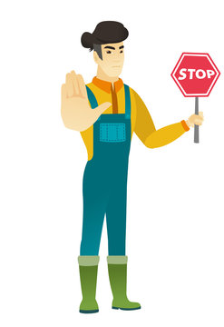 Asian farmer holding stop road sign.
