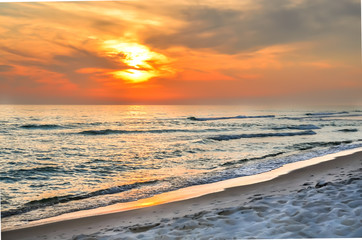 Fototapeta premium Beautiful orange sunset with wispy clouds. Tourist travel destination location. Beach shoreline setting for background or backdrop.