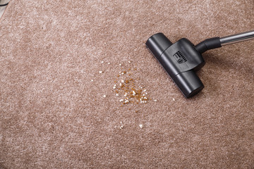 Vacuuming carpet with vacuum cleaner. Dirt on the rug. Housework service. Close up of the head of a...