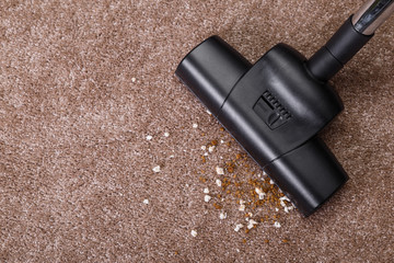 Vacuuming carpet with vacuum cleaner. Dirt on the rug. Housework service. Close up of the head of a...