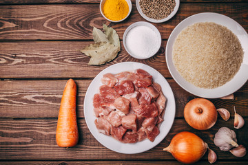 Top view of cooking ingredients on rustic wooden board. Raw meat, onions, carrot