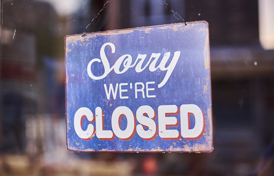 sorry we're closed shop sign hanging in a window