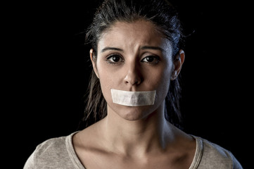 close up portrait of young attractive woman with mouth and lips sealed in adhesive tape restrained