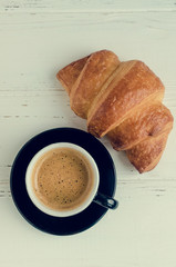 Cup of espresso coffee and fresh baked croissant