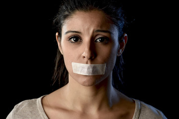 close up portrait of young attractive woman with mouth and lips sealed in adhesive tape restrained