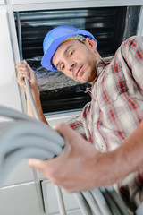 Builder passing cable conduit into roof space