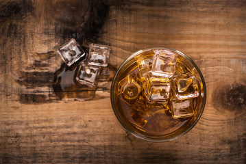 Glass of whiskey on wooden table, view from above