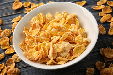 Bowl with cornflakes on grey wooden background, closeup