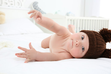 Cute baby wearing funny cap on bed