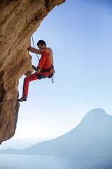Fototapeta premium Young man climbing on overhanging cliff