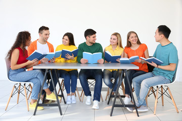 Group of people reading books while sitting at table