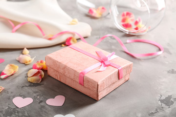 St. Valentines Day concept. Gift box, petals and empty wine glasses on table