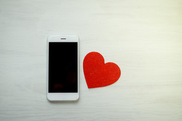 Top view on smart phone and love hearts on wooden desk background. Flat lay style copy space closeup image