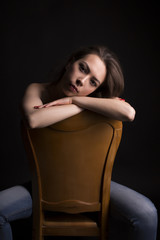 Tanned topless model on a chair in the dark room